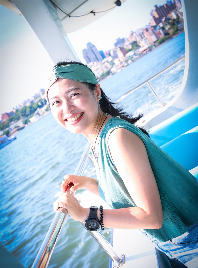在船上扶著欄杆開心大笑的女生